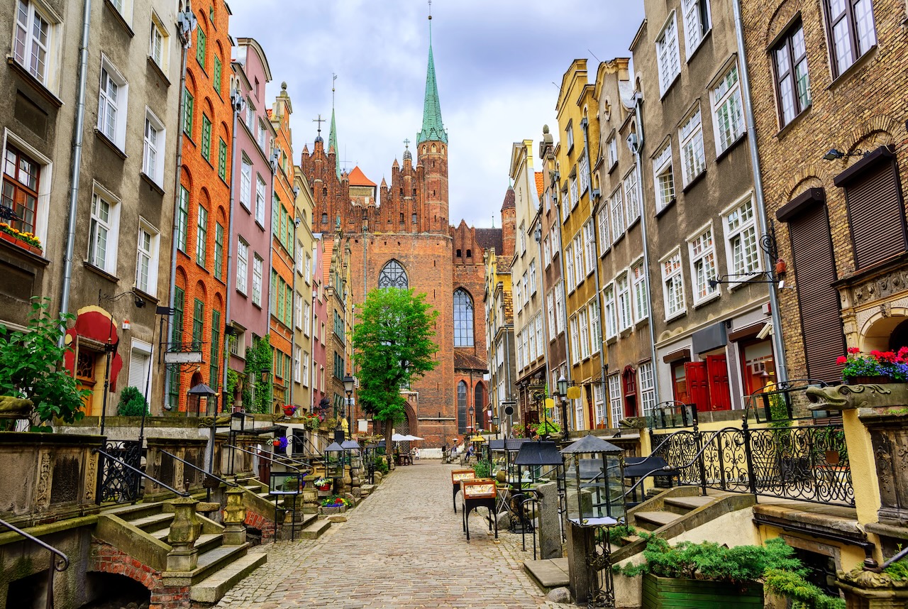 Brostensbelagt gade med farverige gavlhuse og Mariakirken i Gdańsk